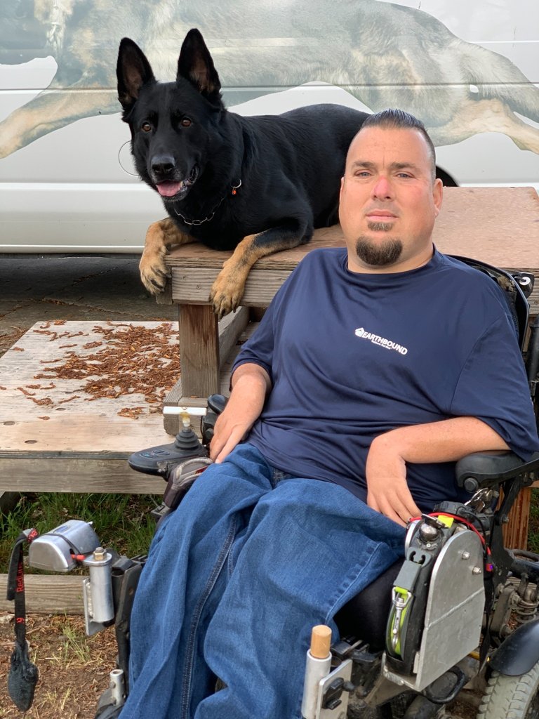 Jason Lake beside a black German Shepherd working dog